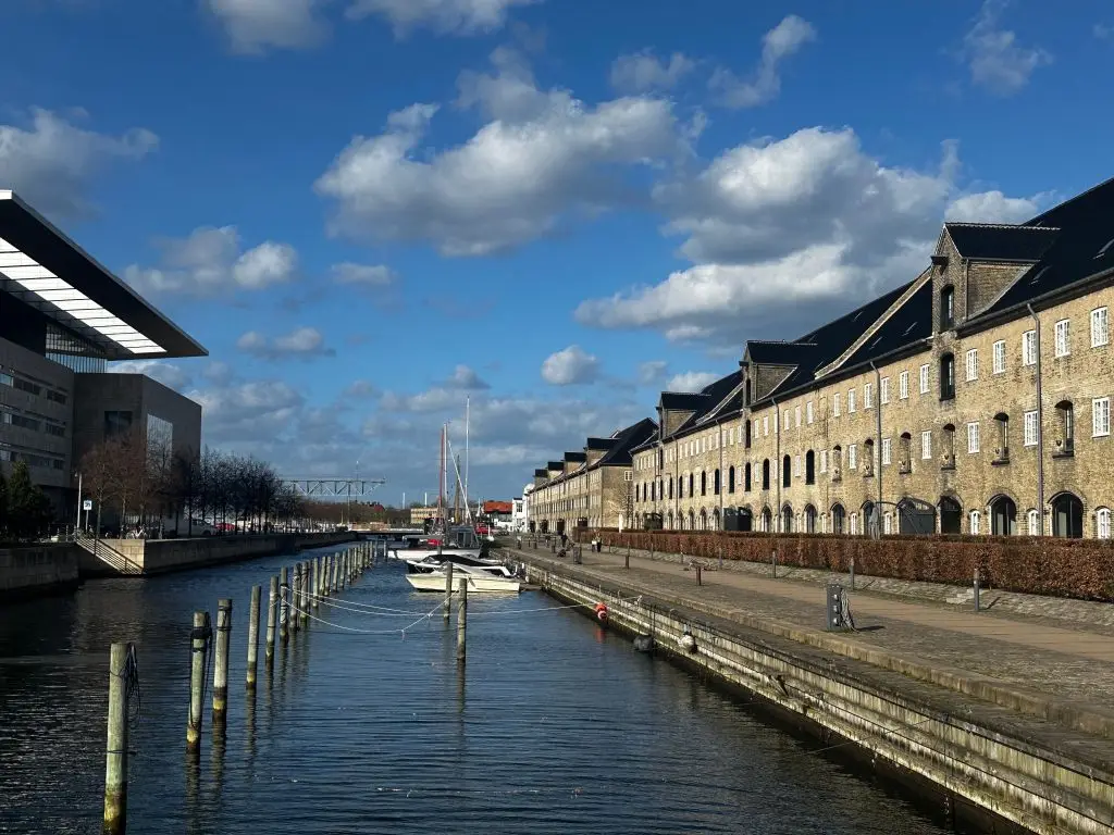 Yellow Row, Copenhagen Calm canal with a row of yellow historic buildings under a blue sky, Copenhagen