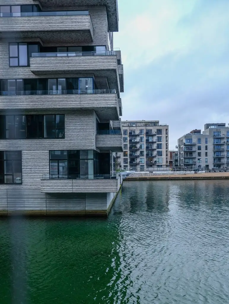 Cantilevered Living, Copenhagen Cantilevered timber-clad apartments rising above green harbour water, Copenhagen