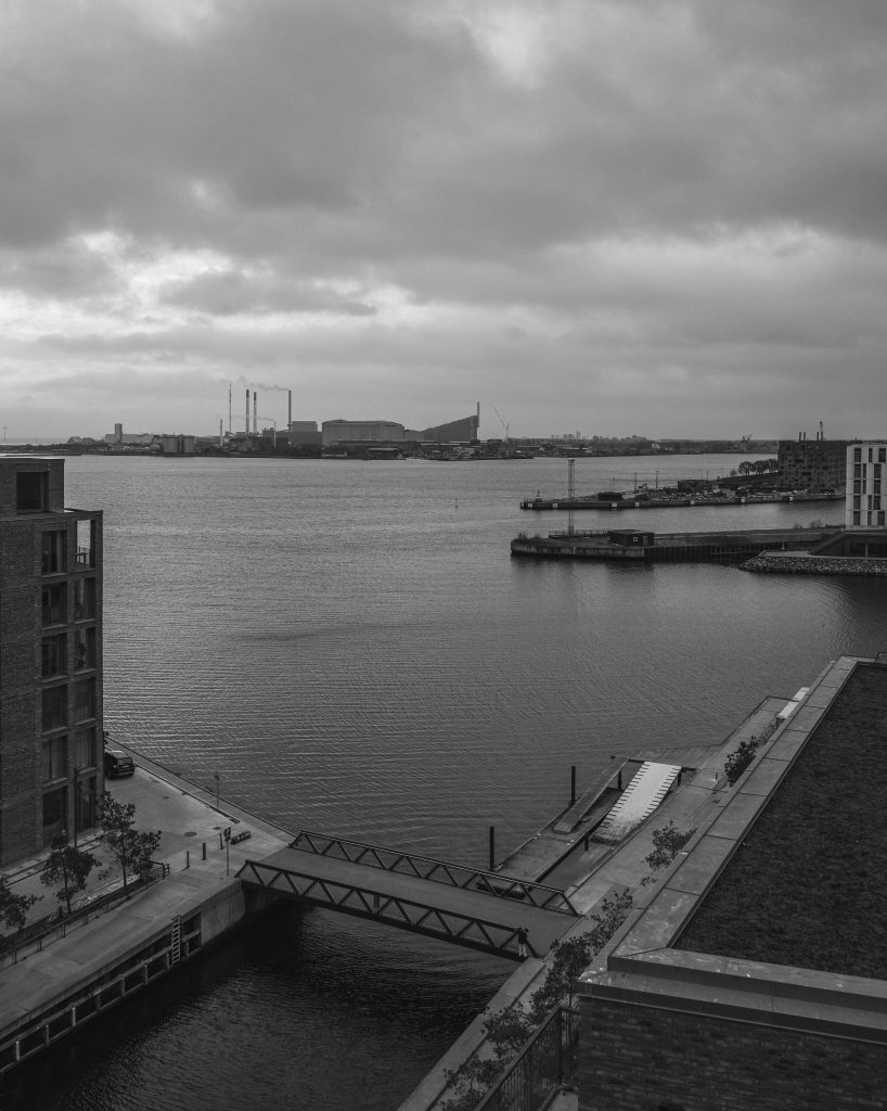 Pier and Skyline, Copenhagen Copenhagen harbour pier and distant skyline under a cloudy sky, black and white