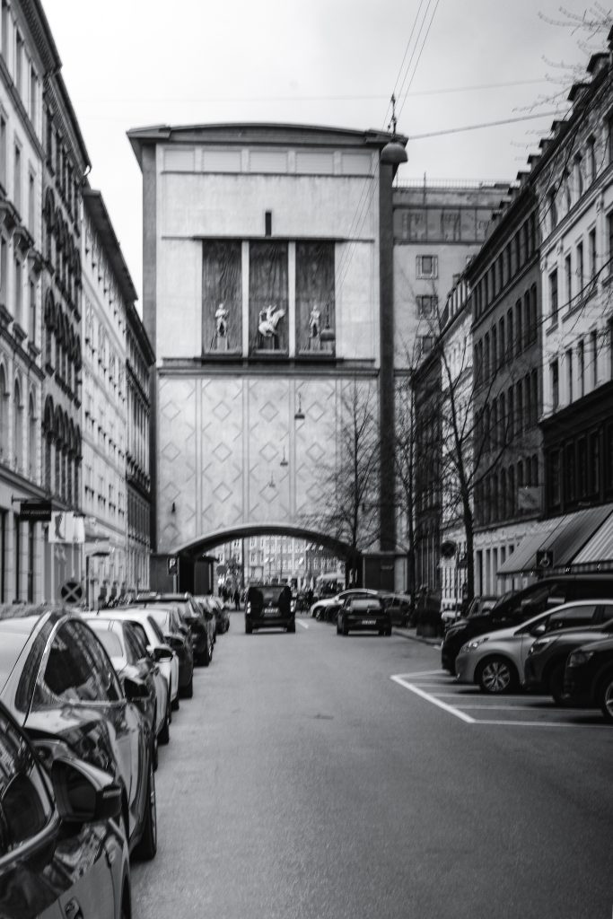 Archway Gate, Copenhagen Street with parked cars leading to a monumental archway gate, Copenhagen, black and white