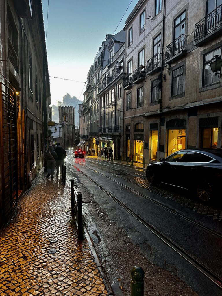 Rain-soaked cobblestone pavement and tram tracks on a street in central Lisbon