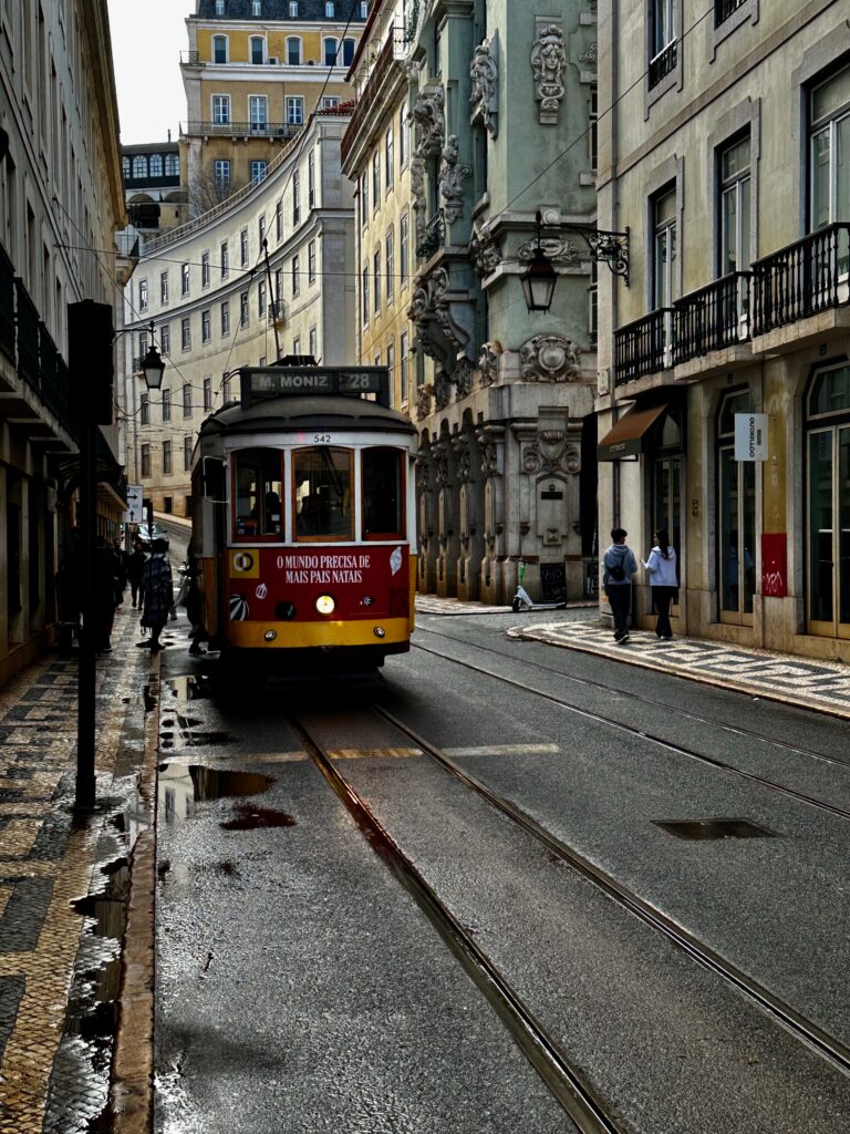 Vintage yellow tram on a narrow rain-soaked street in Lisbon