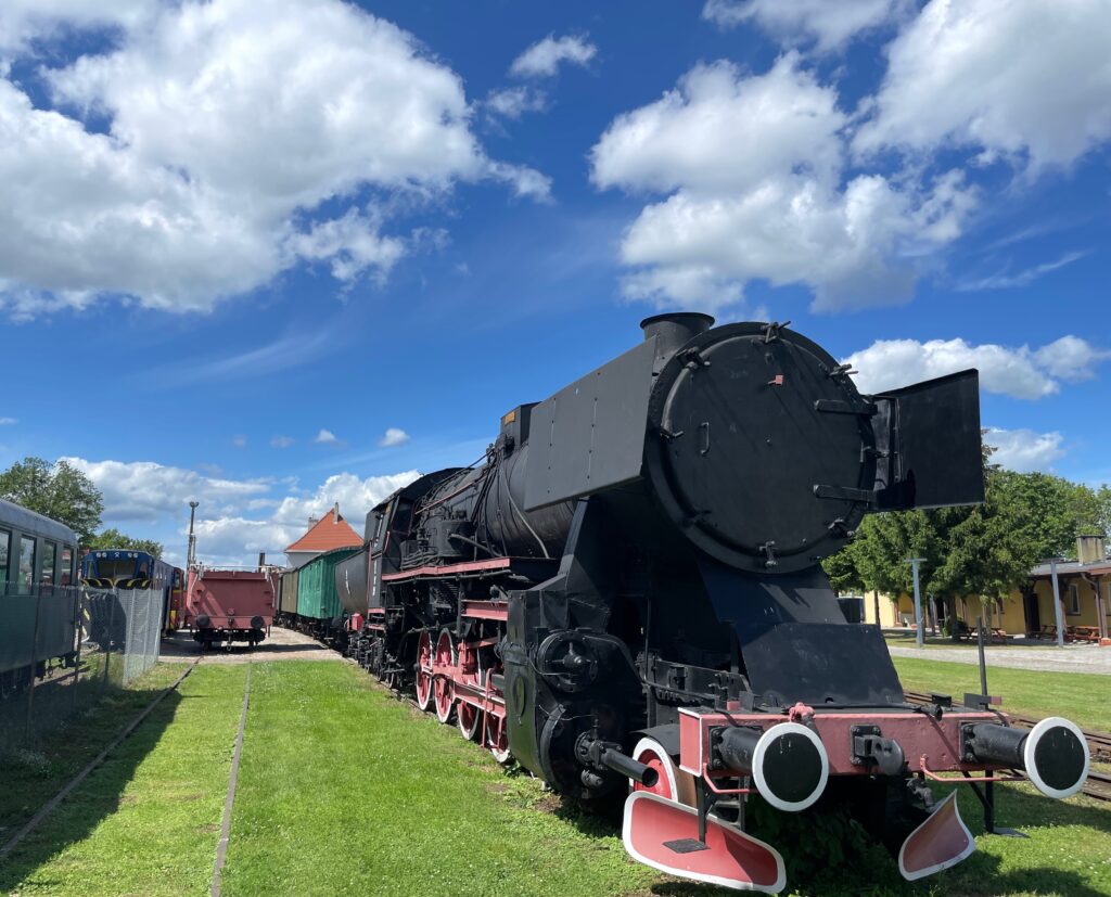 Iron Horse Black steam locomotive with red wheels on display under a blue sky with white clouds
