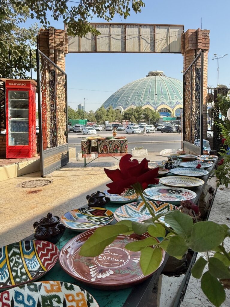 Hand-painted ceramic plates and a rose with the domed Chorsu Bazaar in the background