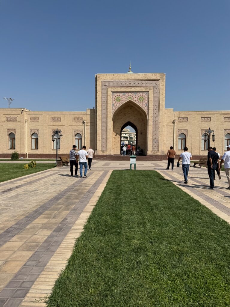 Visitors walking through a grand stone gateway into a Tashkent courtyard