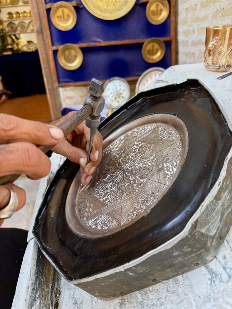 Close-up of an artisan's hands working on a metal plate, Bukhara, Uzbekistan