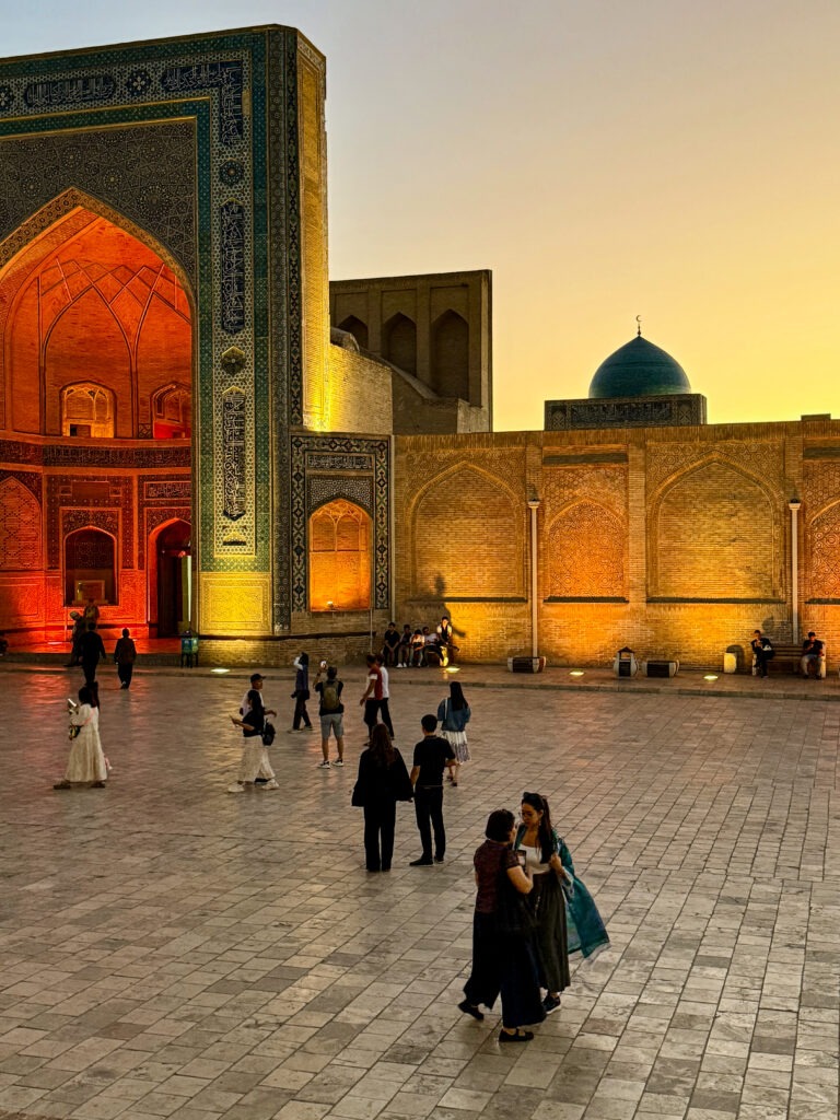 Crowd gathered at a historic arch at sunset, Bukhara, Uzbekistan