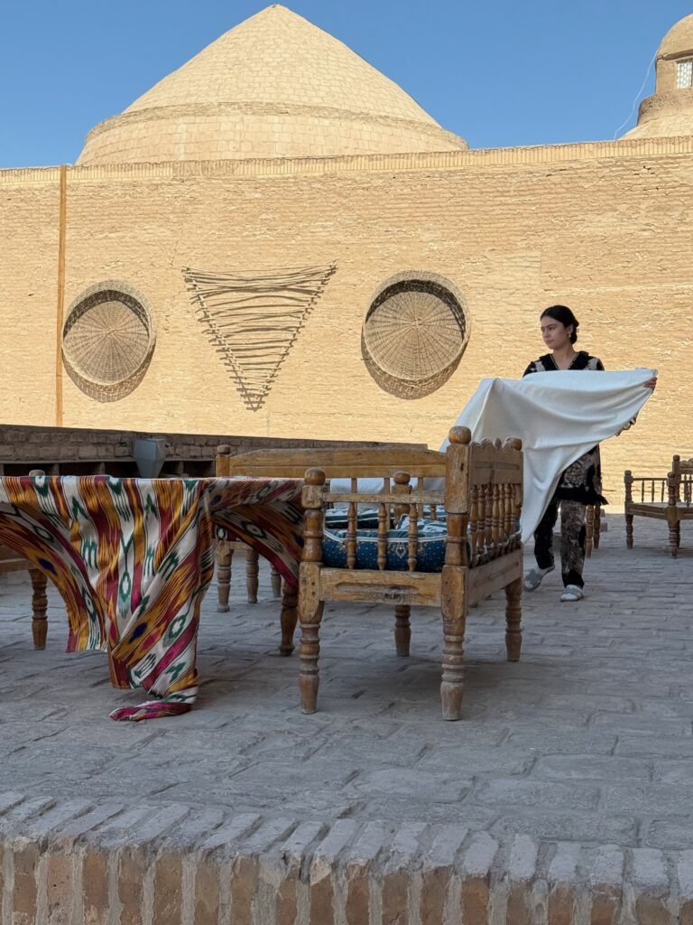 Woman arranging traditional textiles on a rooftop terrace, Khiva, Uzbekistan