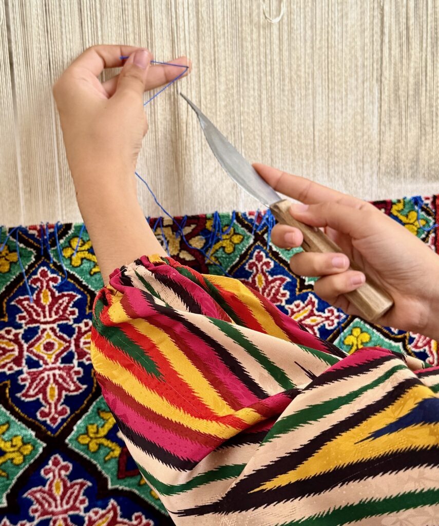 Close-up of hands working with colorful traditional textile, Khiva, Uzbekistan