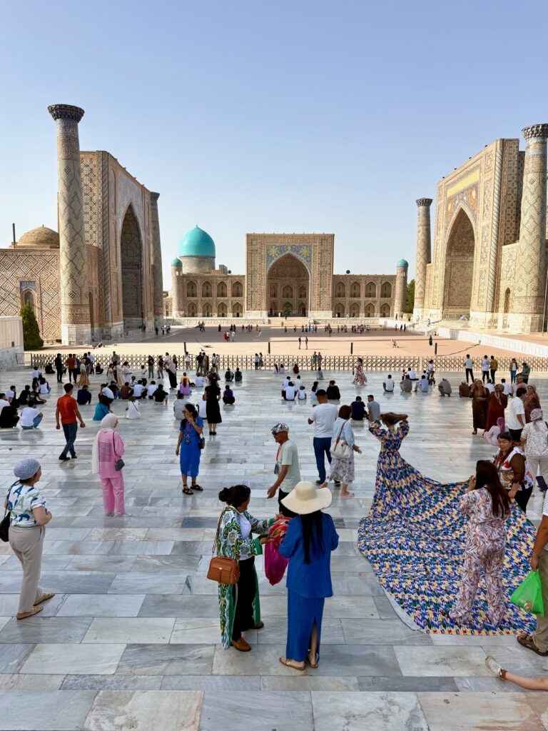 Crowds in colorful dress at Registan Square by day, Samarkand, Uzbekistan