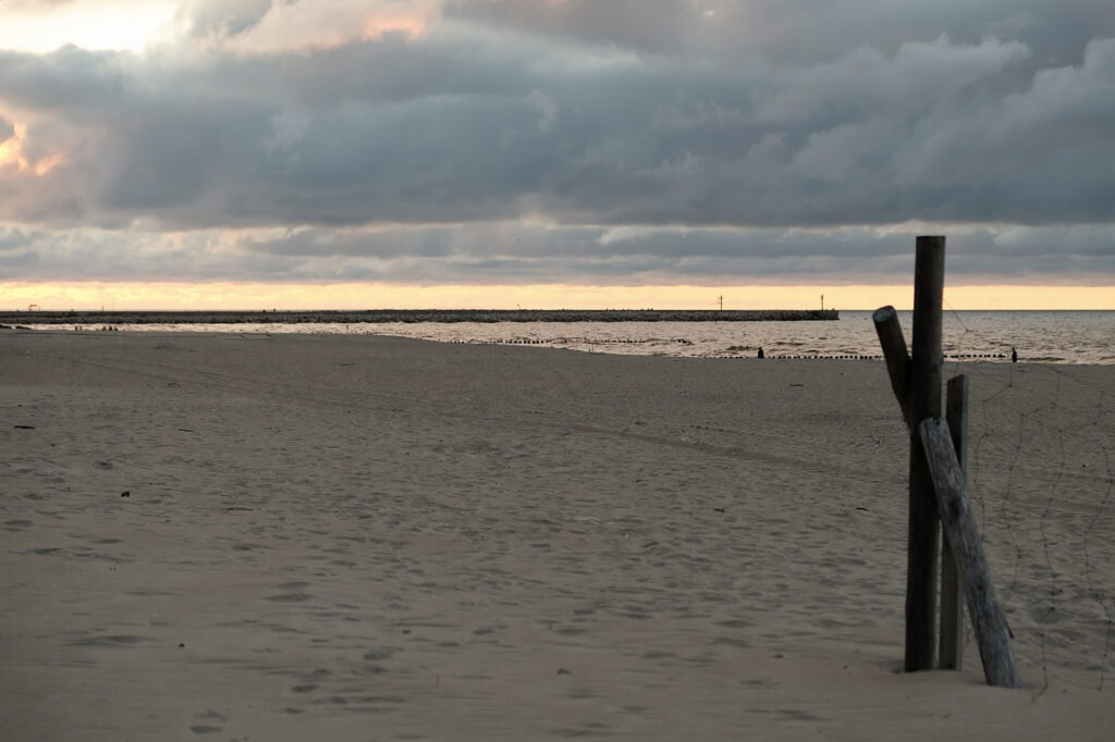 Empty beach with soft evening light and low clouds over the sea, minimalist coastal landscape