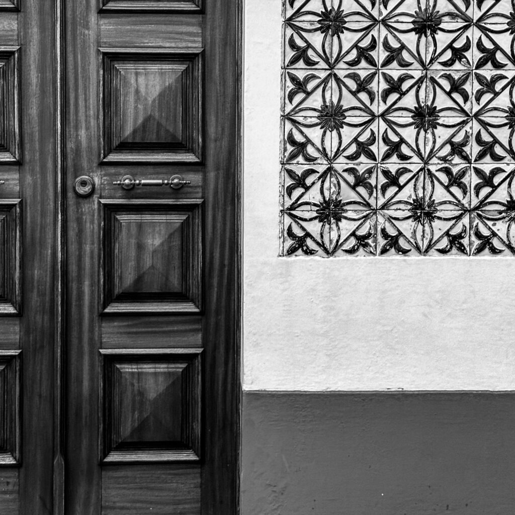 Black and white detail of traditional azulejo tiles and wooden door in an Azores village