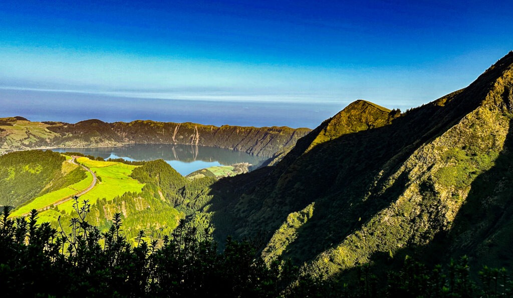 Green volcanic ridges and a crater lake under a deep blue sky, Azores