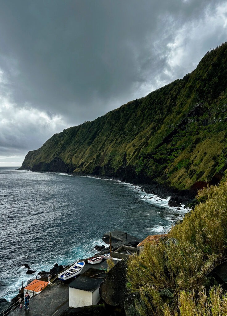 Steep green cliffs above a small coastal village and the Atlantic, Azores