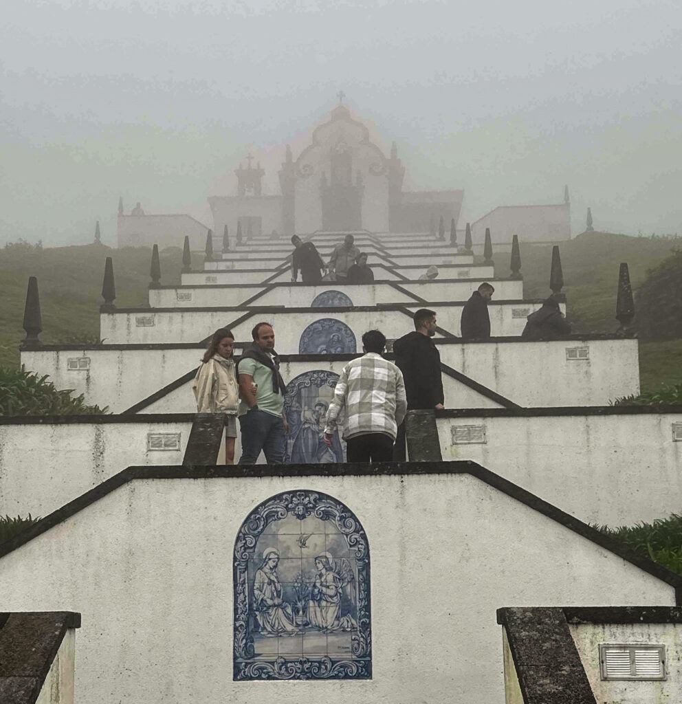 Visitors on the azulejo-lined stairway to Nossa Senhora da Paz chapel in the mist, Vila Franca do Campo, Azores