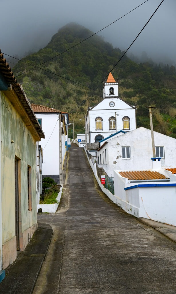 White church at the end of a village street in the mist, Azores
