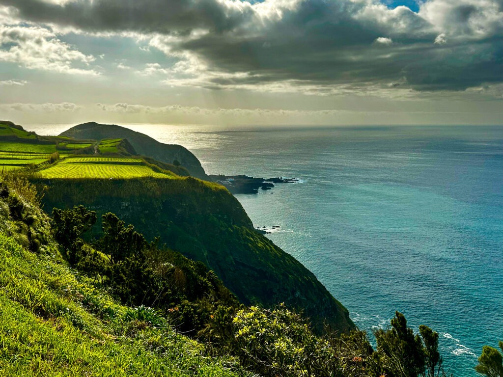 Green coastal cliffs dropping into turquoise ocean under soft sunlight, Azores fine art landscape photography